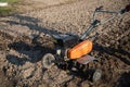 Small plowing machine in hands of a farmer making arable in black soil