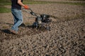 Small plowing machine in hands of a farmer making arable in black soil