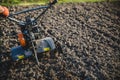 Small plowing machine in hands of a farmer making arable in black soil