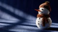A small, plush snowman figurine with a brown hat and scarf sits on a blue surface, casting a shadow under warm lighting. Royalty Free Stock Photo