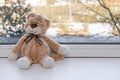 A small plush toy kitten with a bow sits on a white windowsill.