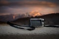 Small pockect size digital camera photographing sunset over mountains