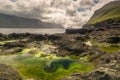 Small pond with green algae on the shore of Kalsoy island, Faroe Islands