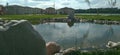 A small pond lined with stones with a view of the gazebos and the river