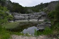 Small pond surrounded by lush greenery and rocky cliffs. The water is stagnant and covered in algae Royalty Free Stock Photo