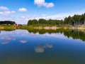 A small pond in the village. Reflection in the water of a blue sky with clouds. Hot summer sunny day.