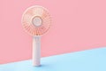 Small portable mini fan on blue and pink background close-up. Royalty Free Stock Photo