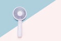 Small portable mini fan on blue and pink background close-up. Royalty Free Stock Photo