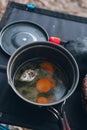 A small portable tourist pot, with a fish soup, a fish dish. It stands on the table. camping breakfast. Vertical photo