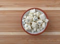 Small portion of crumbled blue cheese in a small bowl on a wood cutting board