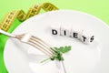 Small portion of food on big plate close-up. Small green parsley leaf on white plate with fork and knife and text diet on the Royalty Free Stock Photo