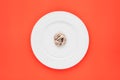 Small portion of tagliatelle pasta on round white plate on orange background.