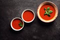 Small portions of Spanish gazpacho in white plates on dark background