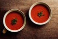 Small portions of Spanish gazpacho in white plates on dark background