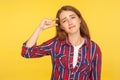 So small! Portrait of disappointed but positive ginger girl in shirt showing a little bit gesture and smirking at camera,