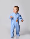 Small positive cute baby boy in blue warm comfortable jumpsuit standing and keeping balance