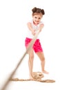 Small positive girl in stylish clothing standing, playing in pulling rope and smiling over white background Royalty Free Stock Photo