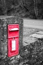 a small postbox sitting on a brick wall near a road