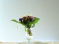 Small posy of spring flowers in a glass vase on a windowsill.