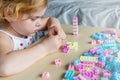 Small preschooler girl playing with colorful toy building blocks, sitting at the table Royalty Free Stock Photo