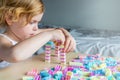 Small preschooler girl playing with colorful toy building blocks, sitting at the table Royalty Free Stock Photo