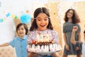 Small pretty girl with pendant chain on her head holds cake with candles at celebration of birthday. Royalty Free Stock Photo