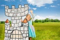Small princess stands behind drawn tower and waves