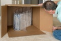 Small product wrapped in plastic wrap inside very large cardboard shipping box as man looks on Royalty Free Stock Photo