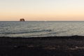 The small promontory of Strombolicchio from Stromboli`s black beach at sunset in Sicily, Italy