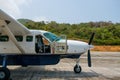 Small propeller airplane with open cockpit door on runway -