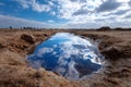 Reflective water puddle in sandy landscape under a blue sky with clouds during daylight Royalty Free Stock Photo
