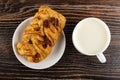 Small puff pie with maple syrup and pecan in plate, cup of milk on wooden table. Top view