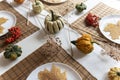 Small pumpkins and dry brown maple leafs on white plates, autumn dinner table