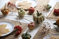 small pumpkins and dry brown maple leafs on white plates, autumn dinner table