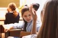 Small pupils in the lesson. It`s elementary school students. Girl diligently writes,. On a school desk there are