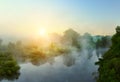 Small quiet river at dawn, green overgrown coast meandering river, fog, mist over the water. Royalty Free Stock Photo