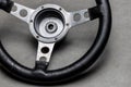 small racing steering wheel with black leather made of aluminum on a polished concrete floor, used steering wheel, a sign for