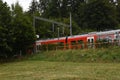 Small railway platform for passengers in local train station with red electric train