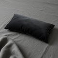 A small rectangular black pillow rests on a dark grey bedspread. The fabric appears Royalty Free Stock Photo