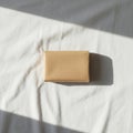 A small rectangular package wrapped in light brown paper lies on a white fabric surface Royalty Free Stock Photo