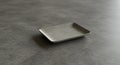 A small, rectangular tray rests on a smooth, gray stone or ceramic surface. The tray Royalty Free Stock Photo