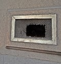 small, rectangular window set into a stone wall, metal grille close-up