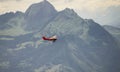 A small red airplane flying over the Alps Royalty Free Stock Photo