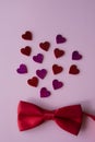 Small red bow tie and pink background with hearts top view. St. Valentines Day. greeting card Royalty Free Stock Photo
