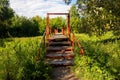 A small red bridge with wooden flooring and iron arches over a small forest river Royalty Free Stock Photo