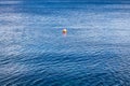 Small red buoy on a background of blue sea. Minimalist picture of the sea and the red object. Royalty Free Stock Photo