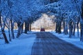 Small red car carefully driving on the ice and snow covered small asphalt road. Royalty Free Stock Photo