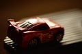 Small red car toy in dark room with bright light Royalty Free Stock Photo