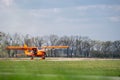 Small red charter airplane waiting on a green field to take off