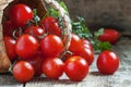 Small red cherry tomatoes spill out of a wicker basket on an old Royalty Free Stock Photo